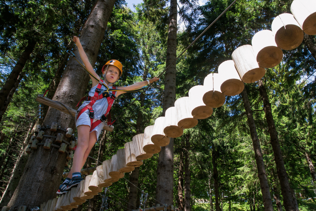 Enfant traversant pont suspendu dans la forêt.