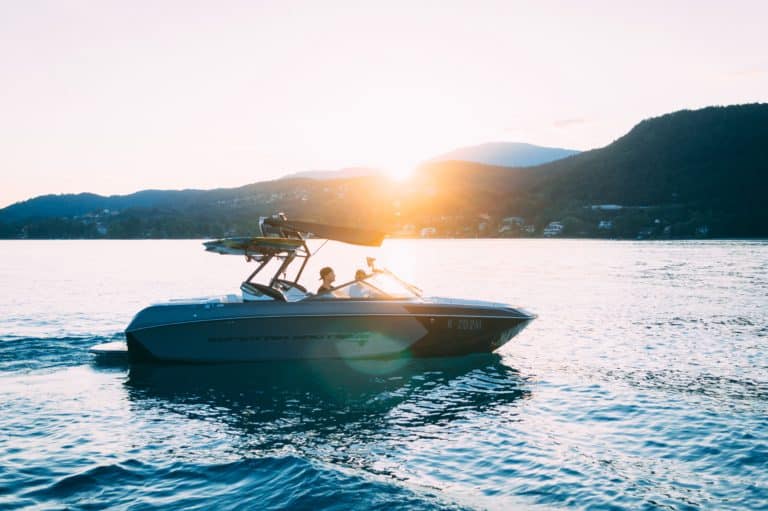 Bateau naviguant au coucher du soleil sur lac.